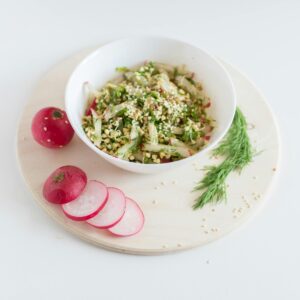 A healthy vegan salad with buckwheat, radish, and dill garnished with sesame seeds.